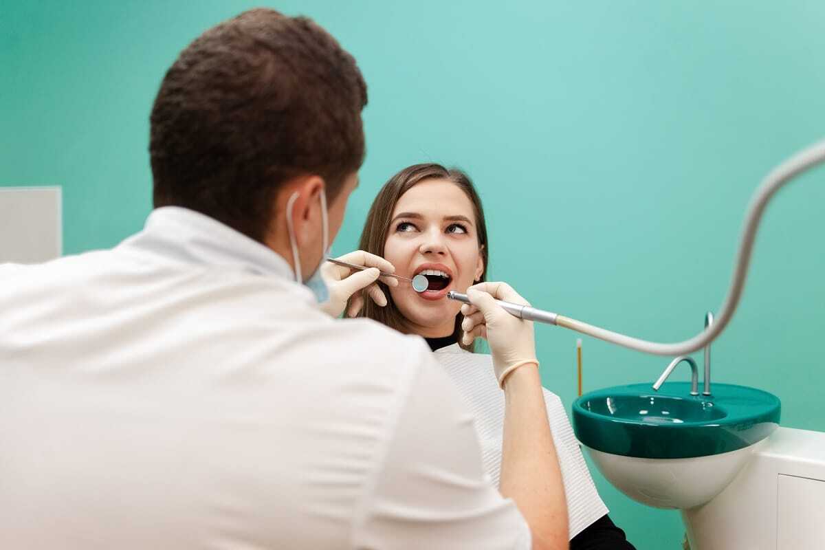 Dentist examining patient's teeth during oral examination in dental office.