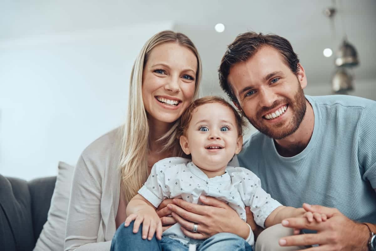 Happy family with young child smiling together at home dental care visit.
